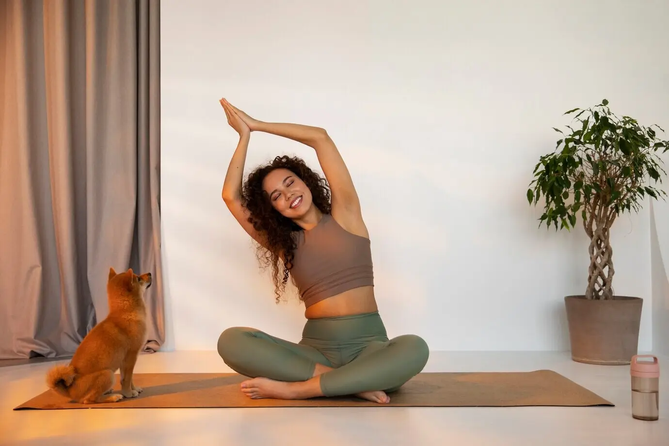 Снято в полный рост: подтянутая женщина занимается спортом с собакой в помещении.